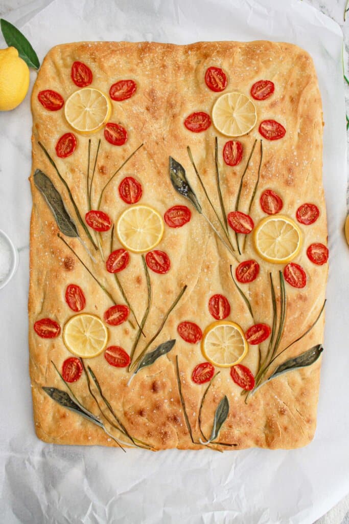 finished tomato focaccia bread on a parchment lined baking sheet,