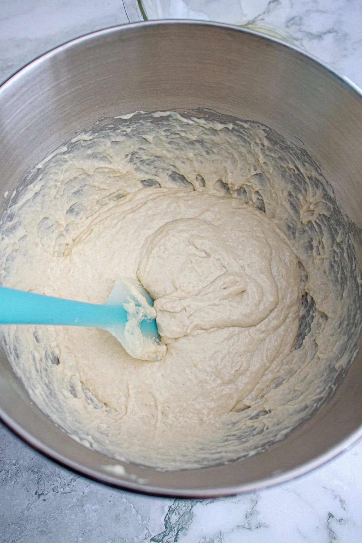 dough being mixed in a stainless steel mixing bowl.