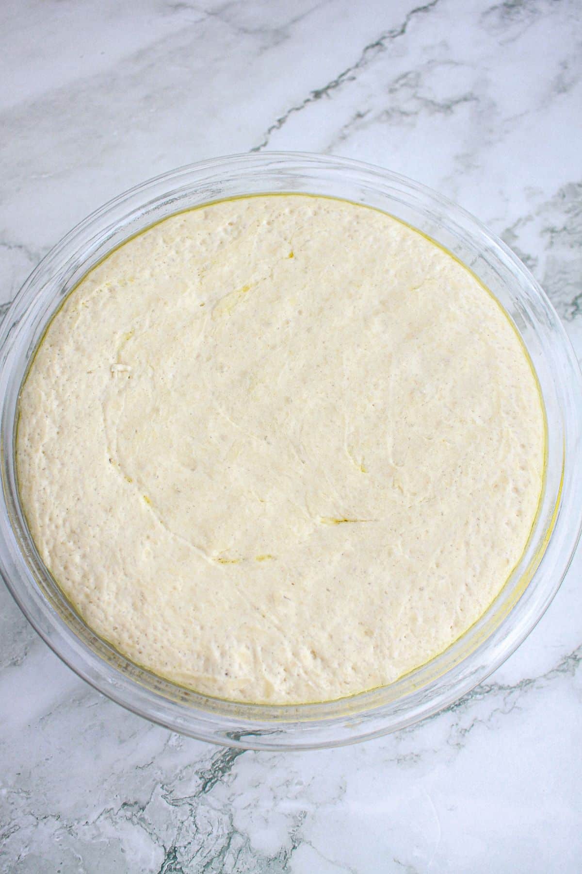 dough rising in a glass mixing bowl.