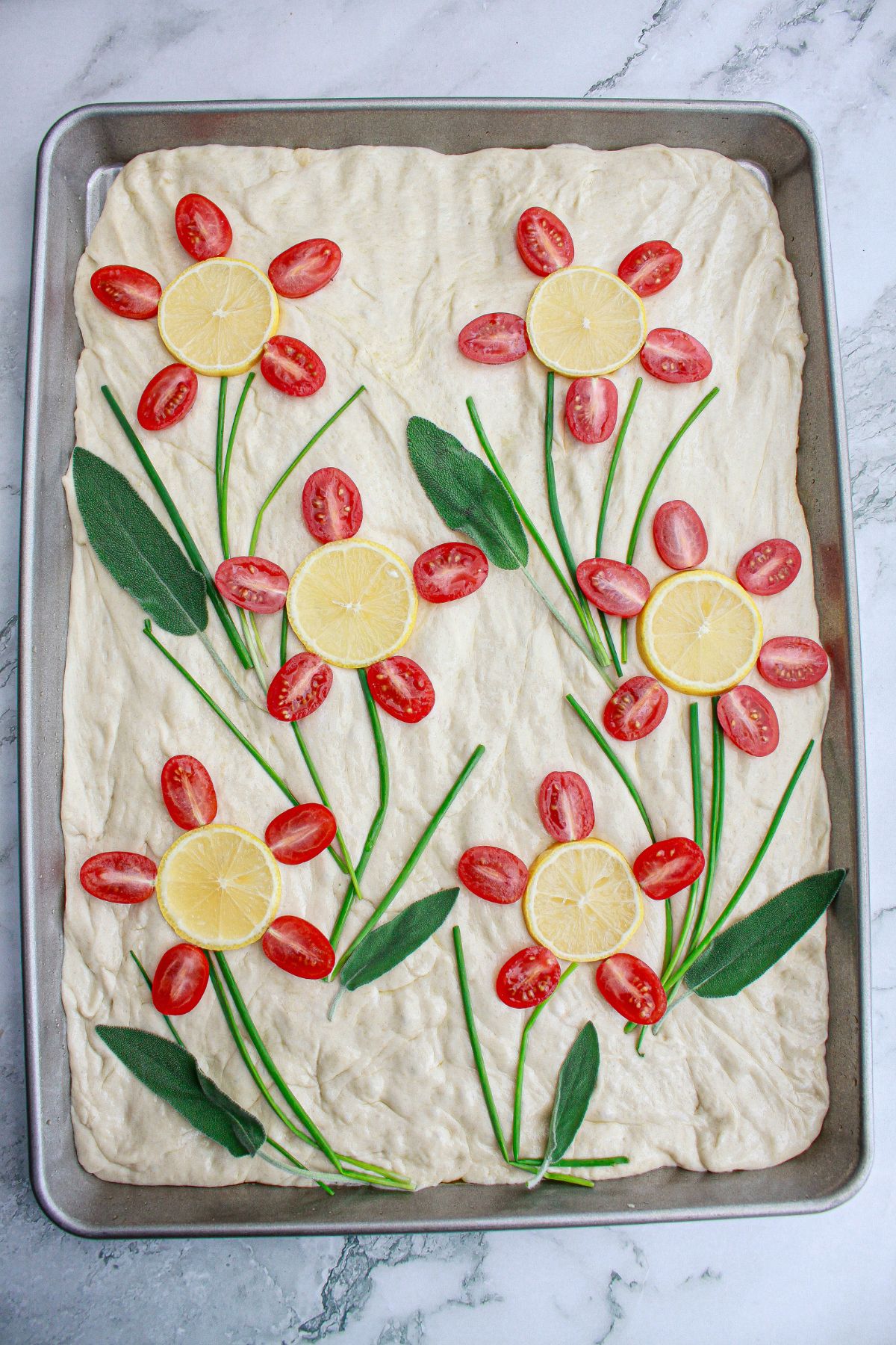 raw finished tomato focaccia bread on a parchment lined baking sheet,