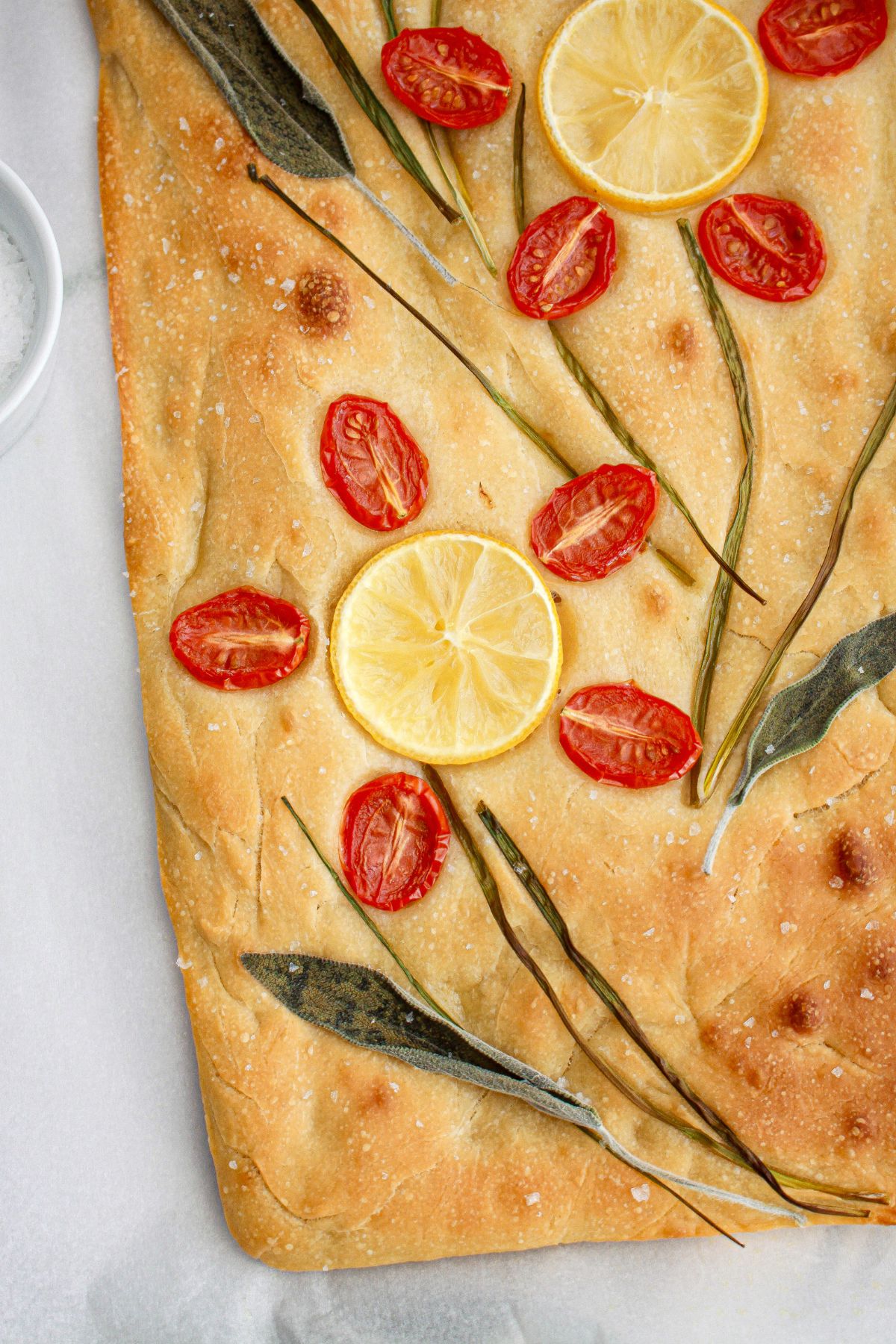 finished tomato focaccia bread on a parchment lined baking sheet,