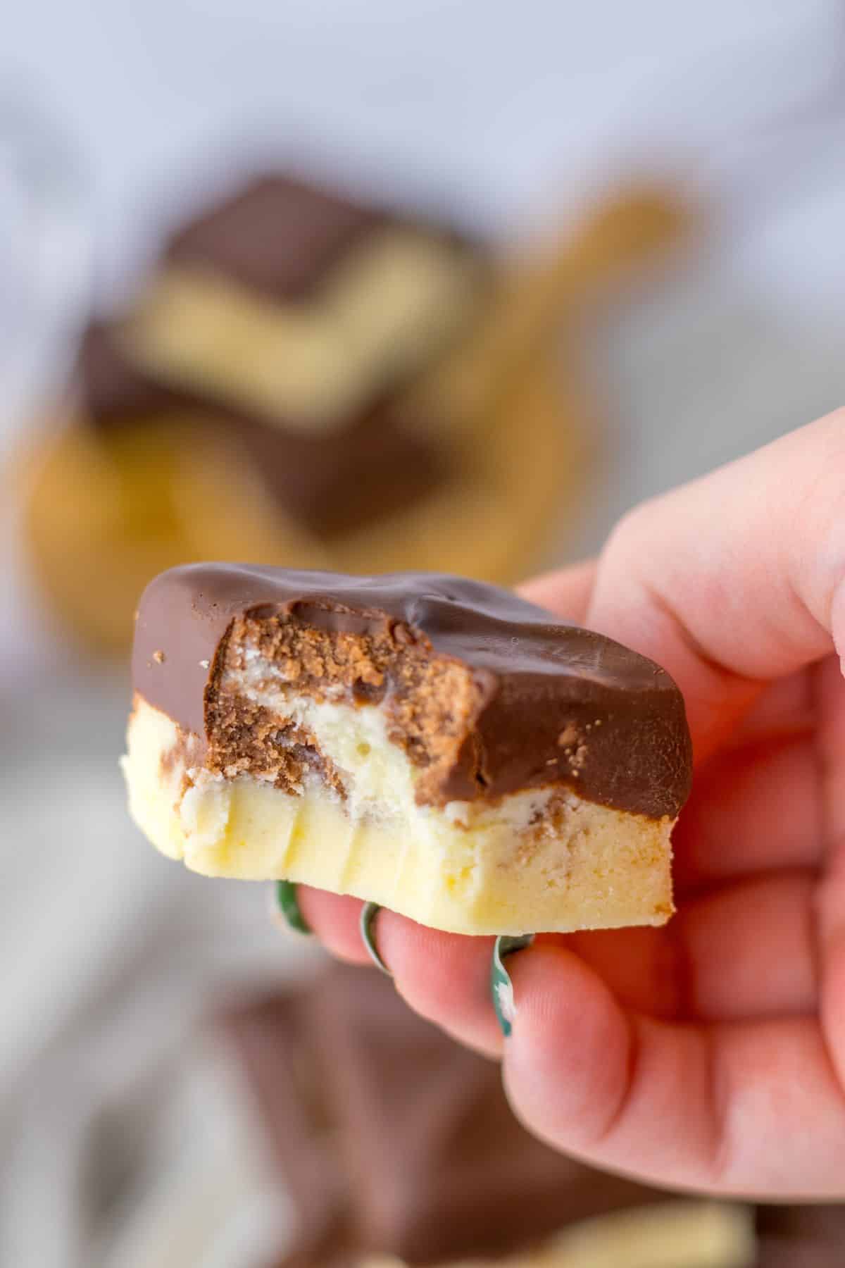 piece of boston cream fudge held in a woman's hand in the air.