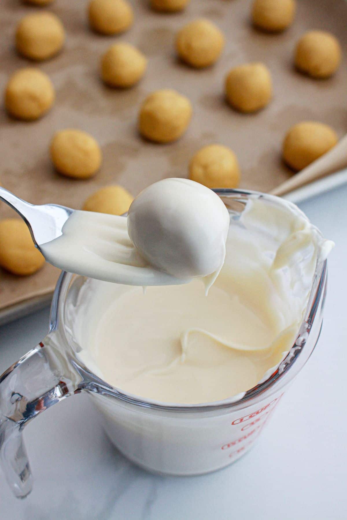 truffle being dipped in a white chocolate with a fork.