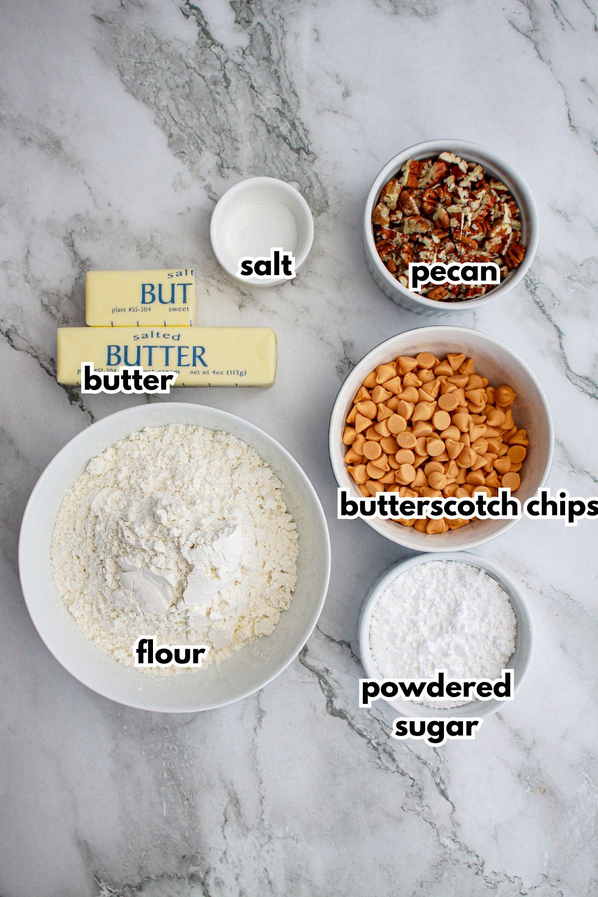 salt, pecans, butter, flour, powdered sugar, and butterscotch chips on a marble counter.