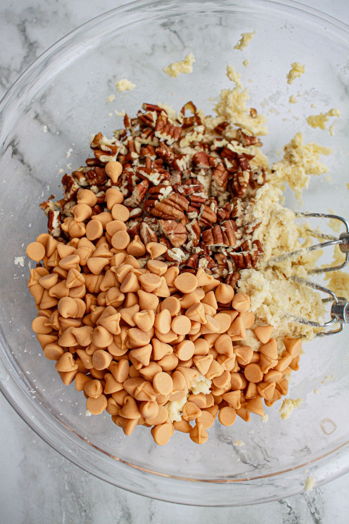 cookie dough and butterscotch chips and pecans in a large glass bowl.