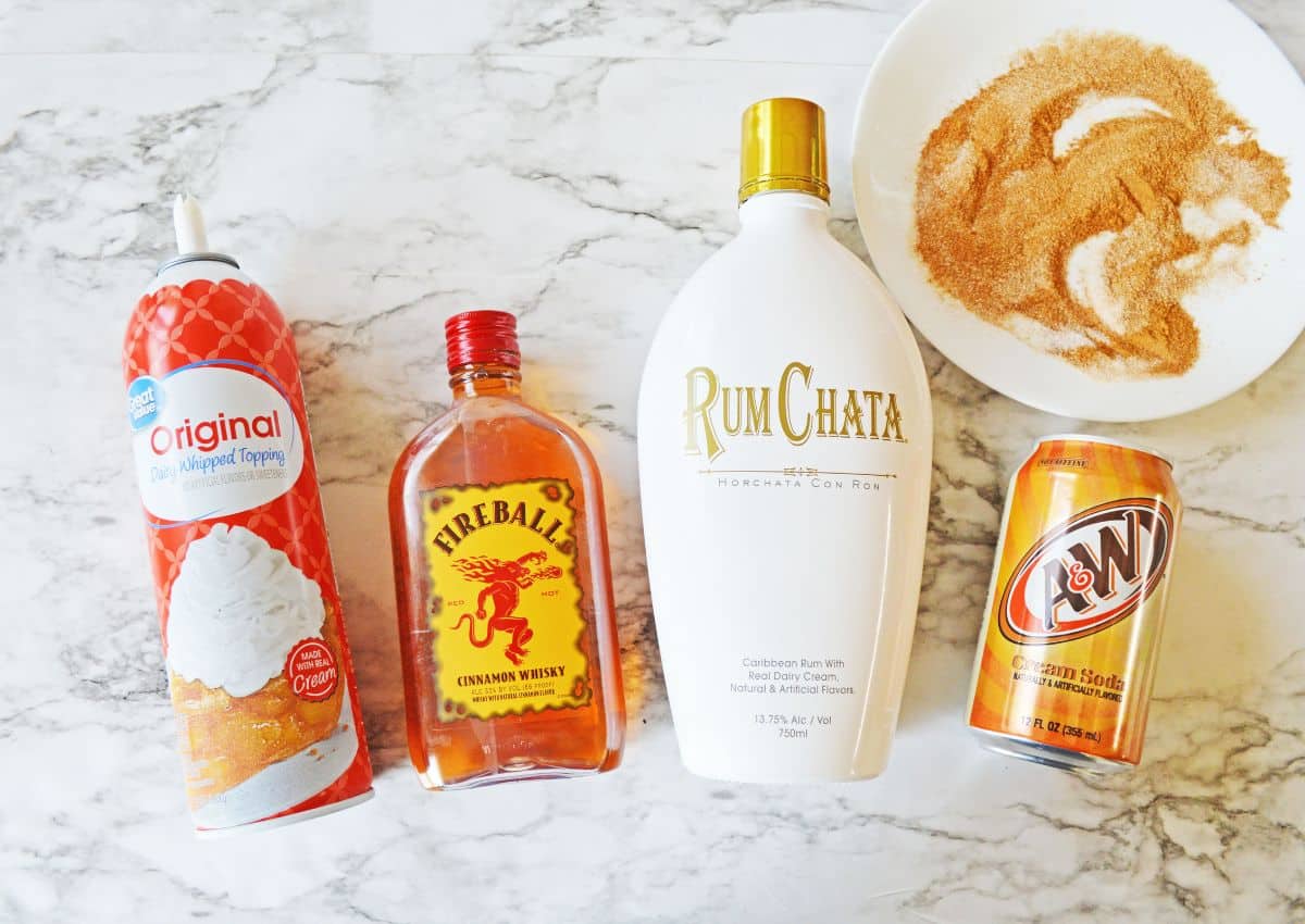 bottles of whipped cream, fireball, rumchata, cream soda, and cinnamon sugar on a plate.