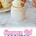 cinnamon roll cocktail on a marble counter topped with whipped cream and a cinnamon stick.