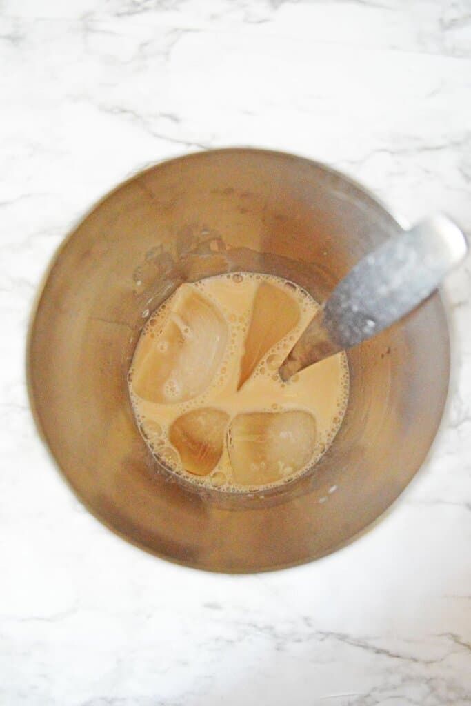 alcohol being stirred with ice in a cocktail shaker.