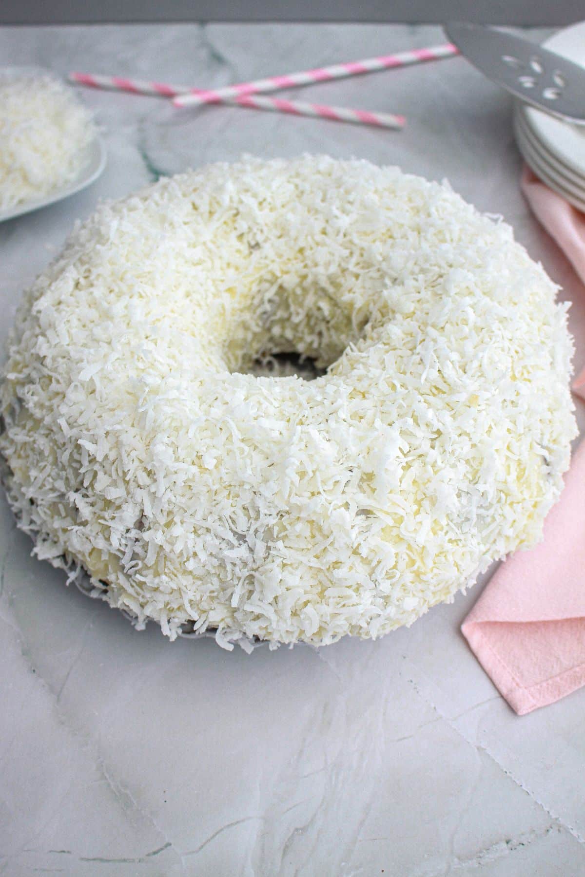 whole uncut coconut white chocolate cake on a plate.