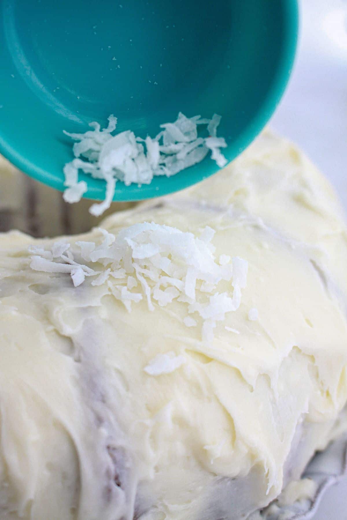 coconut being sprinkled on top of the cake.