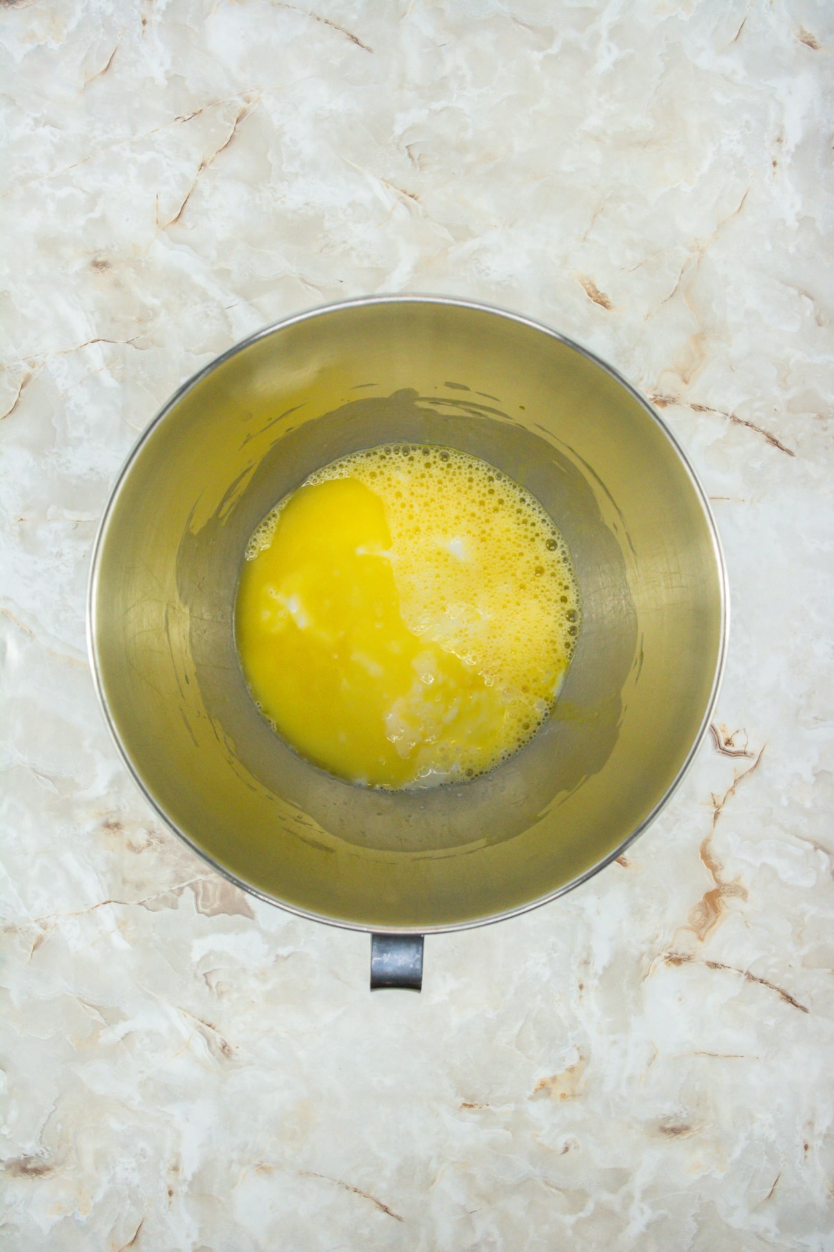 eggs and buttermilk being mixed in a stainless steel mixing bowl.