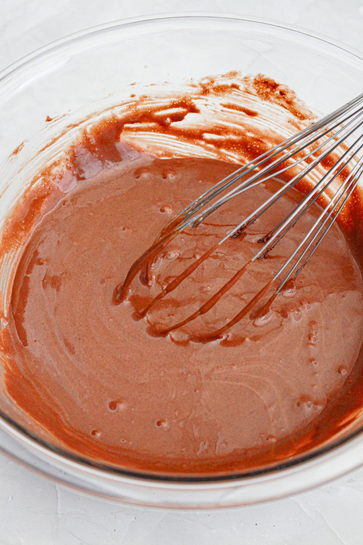 cookie dough being mixed in a large glass mixing bowl.