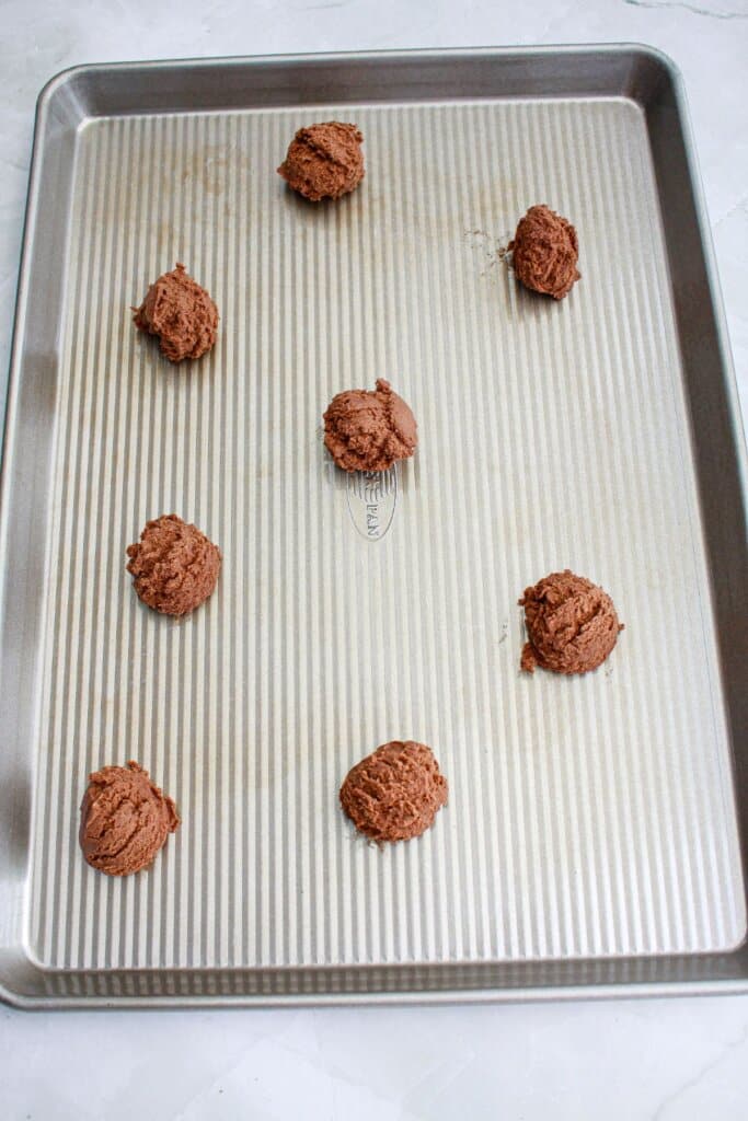 cookie dough balls on a baking sheet ready for the oven.