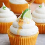 honey being drizzled on top of honey lime cupcakes.