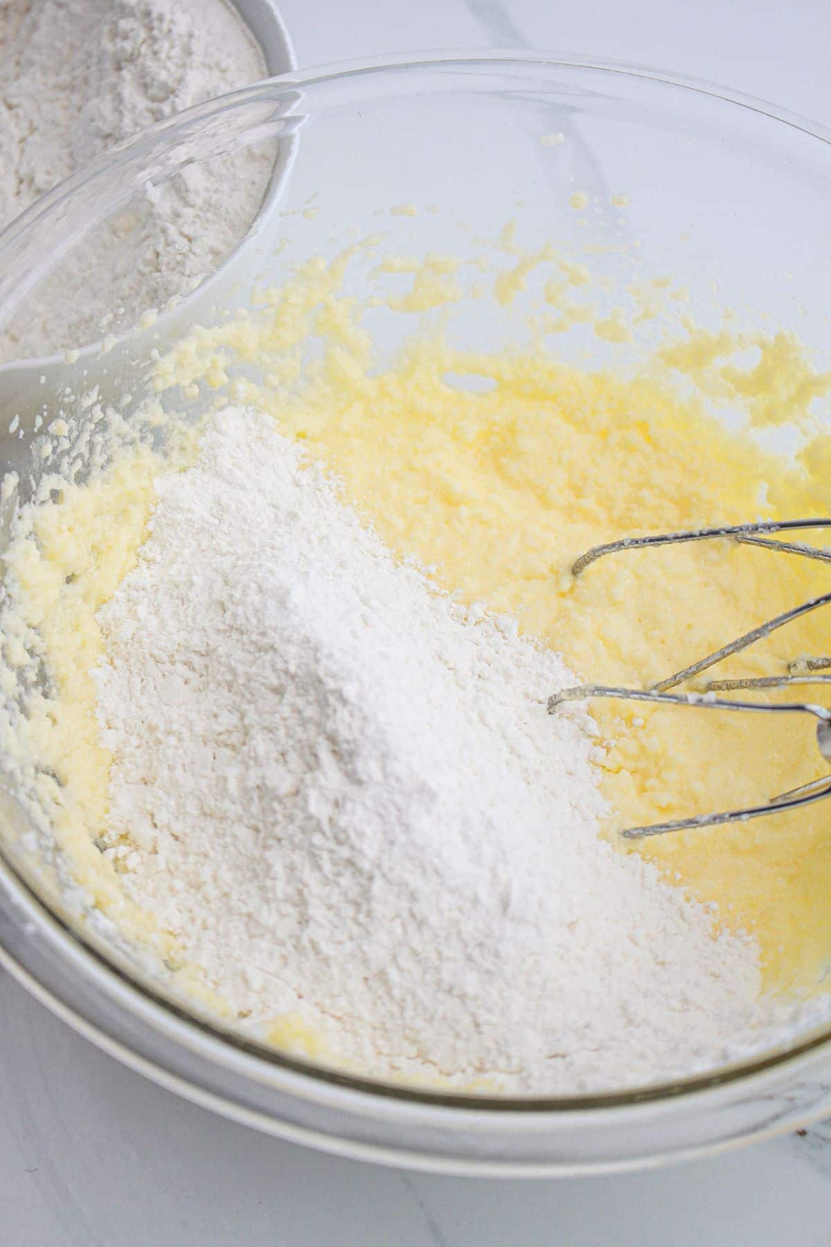 dry ingredients being added to batter in a glass mixing bowl.