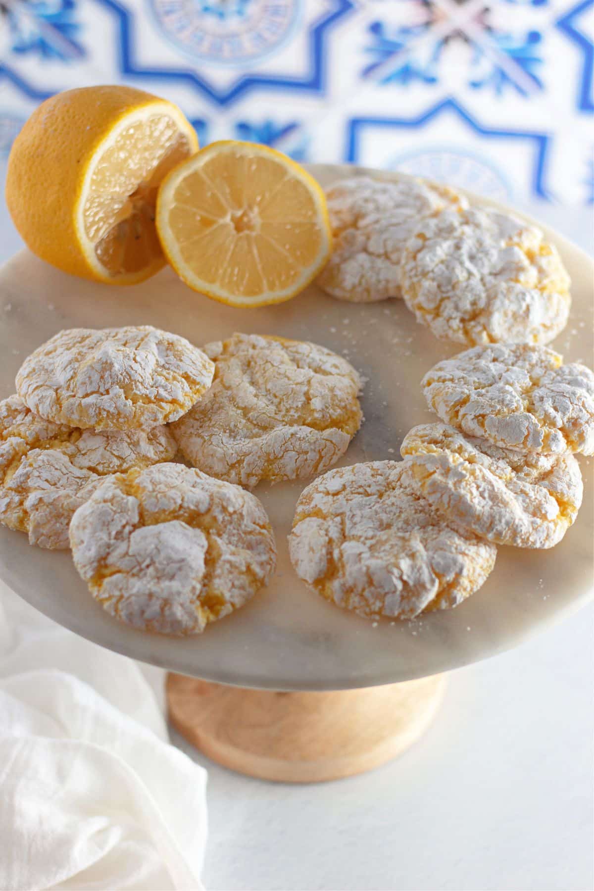lemon cool whip cookies on a cake stand with a lemon.