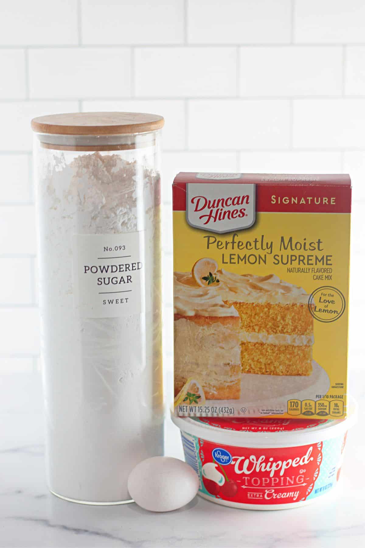 containers of powdered sugar, egg, lemon cake mix, and whipped topping.