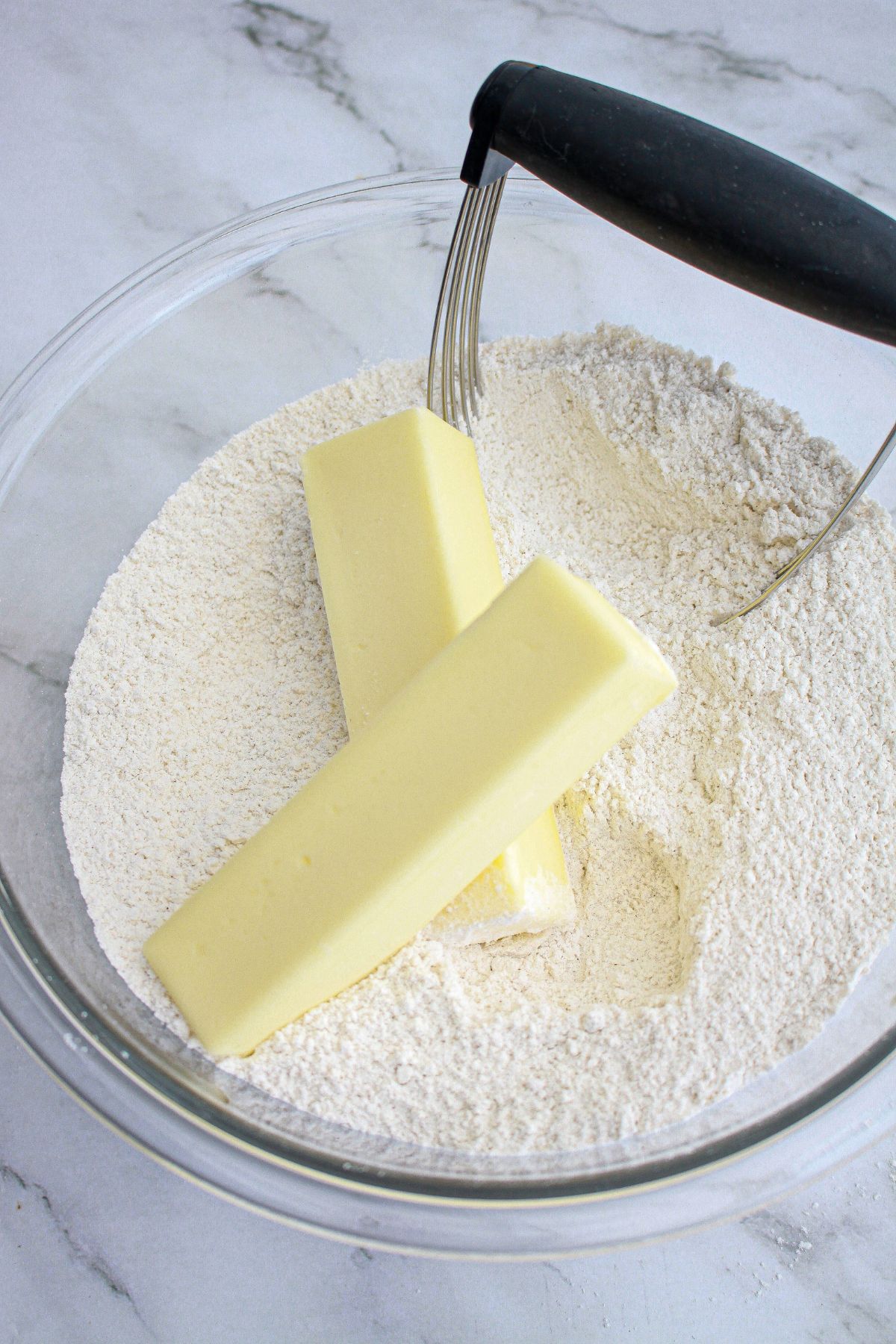 butter being mixed into a flour with a pastry cutter.