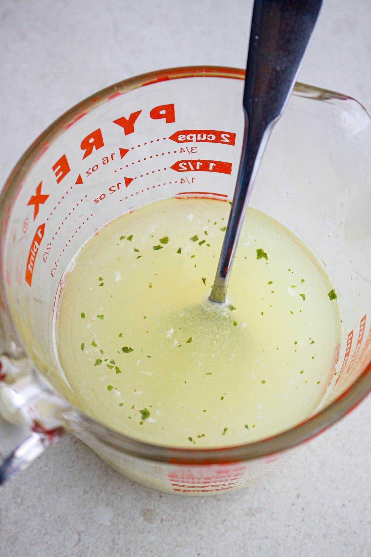 lemon juice and chicken stock being mixed in a glass measuring cup.