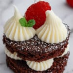 mini chocolate cake on a plate topped with a fresh raspberry,