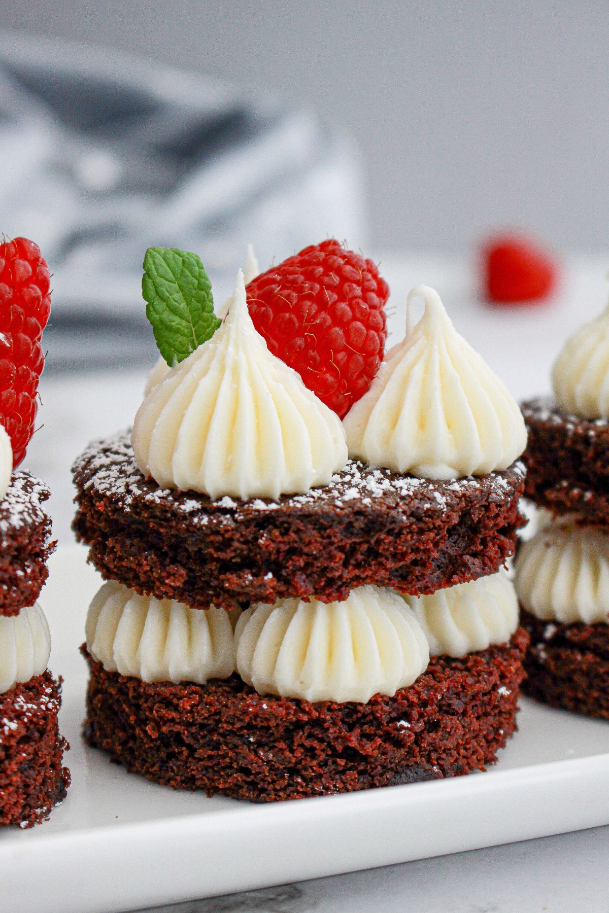 mini chocolate cake on a plate topped with a fresh raspberry.