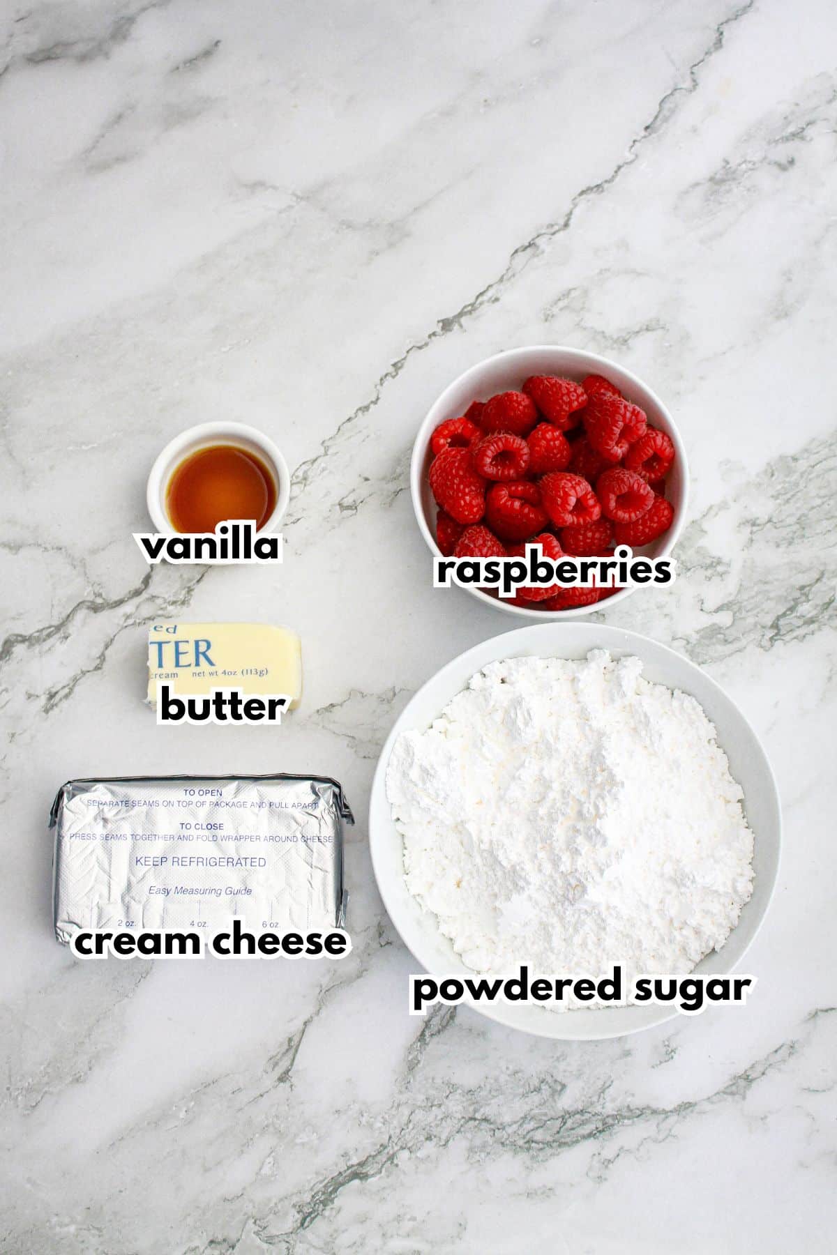 bowls of vanilla, butter, cream cheese, raspberries, powdered sugar on a counter to make the frosting.