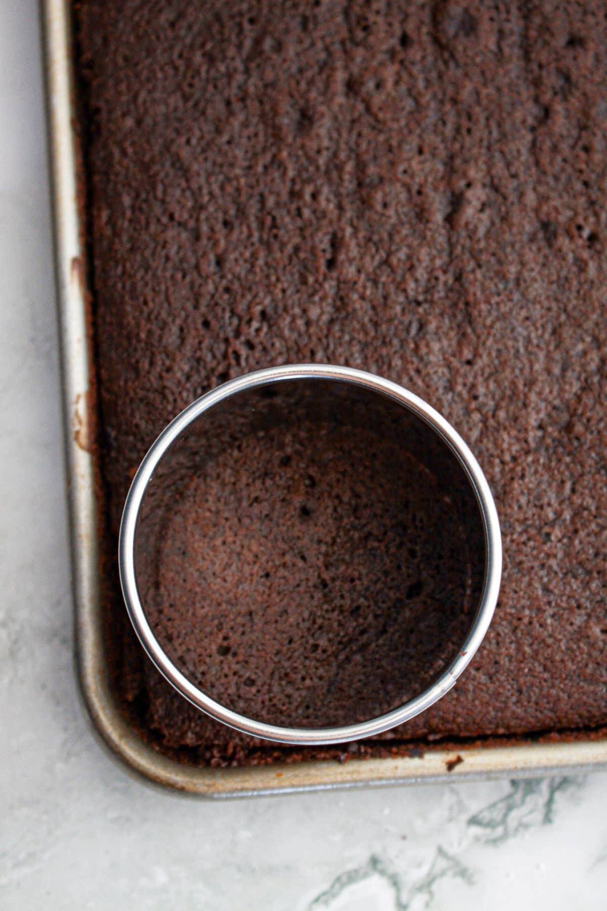 chocolate cake being cutting into small circles with a metal cookie cutter.