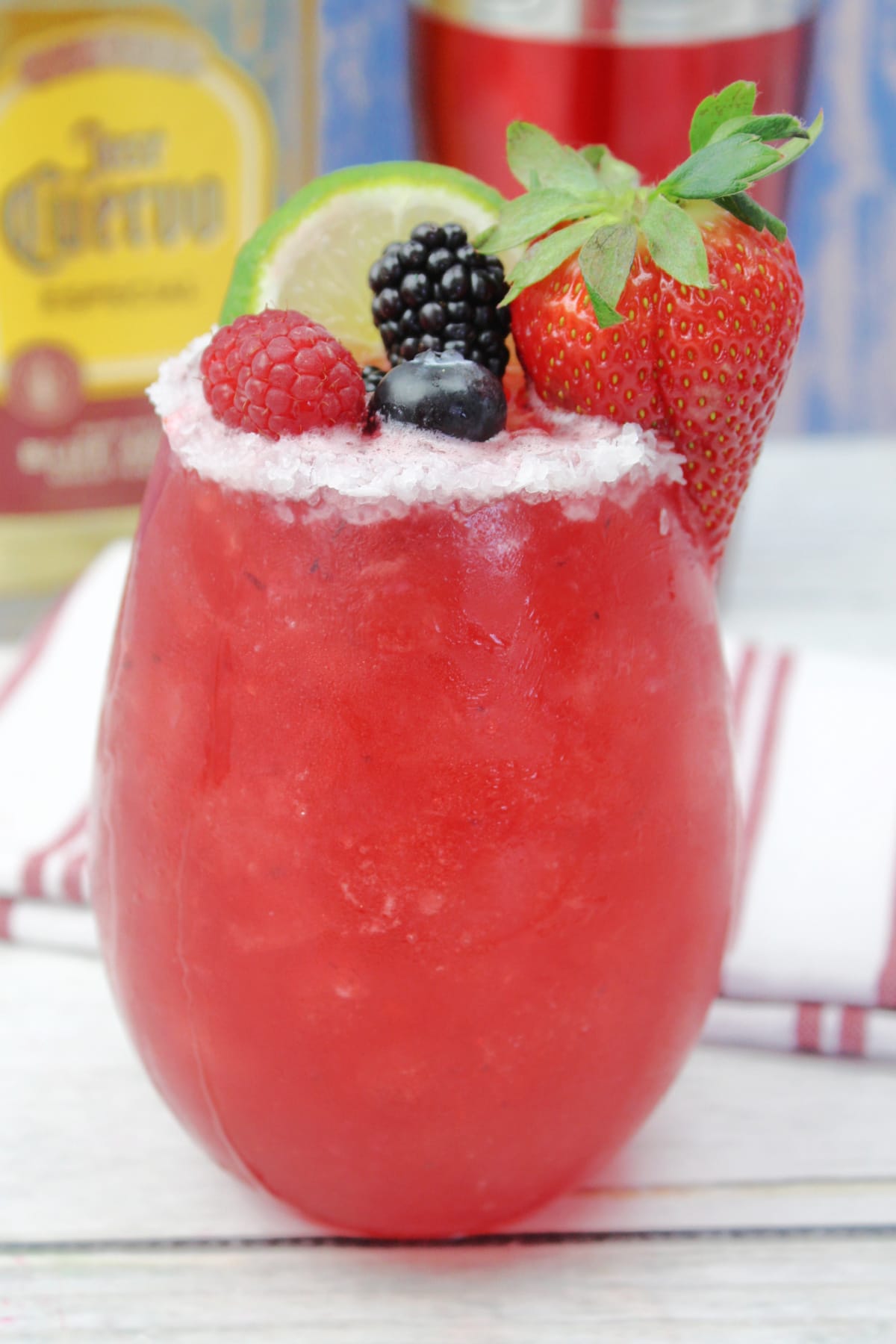 mixed berry cocktail garnished with a lime wedge, strawberry, blueberry, blackberry, and a raspberry.