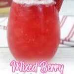 mixed berry cocktail garnished with a lime wedge, strawberry, blueberry, blackberry, and a raspberry.