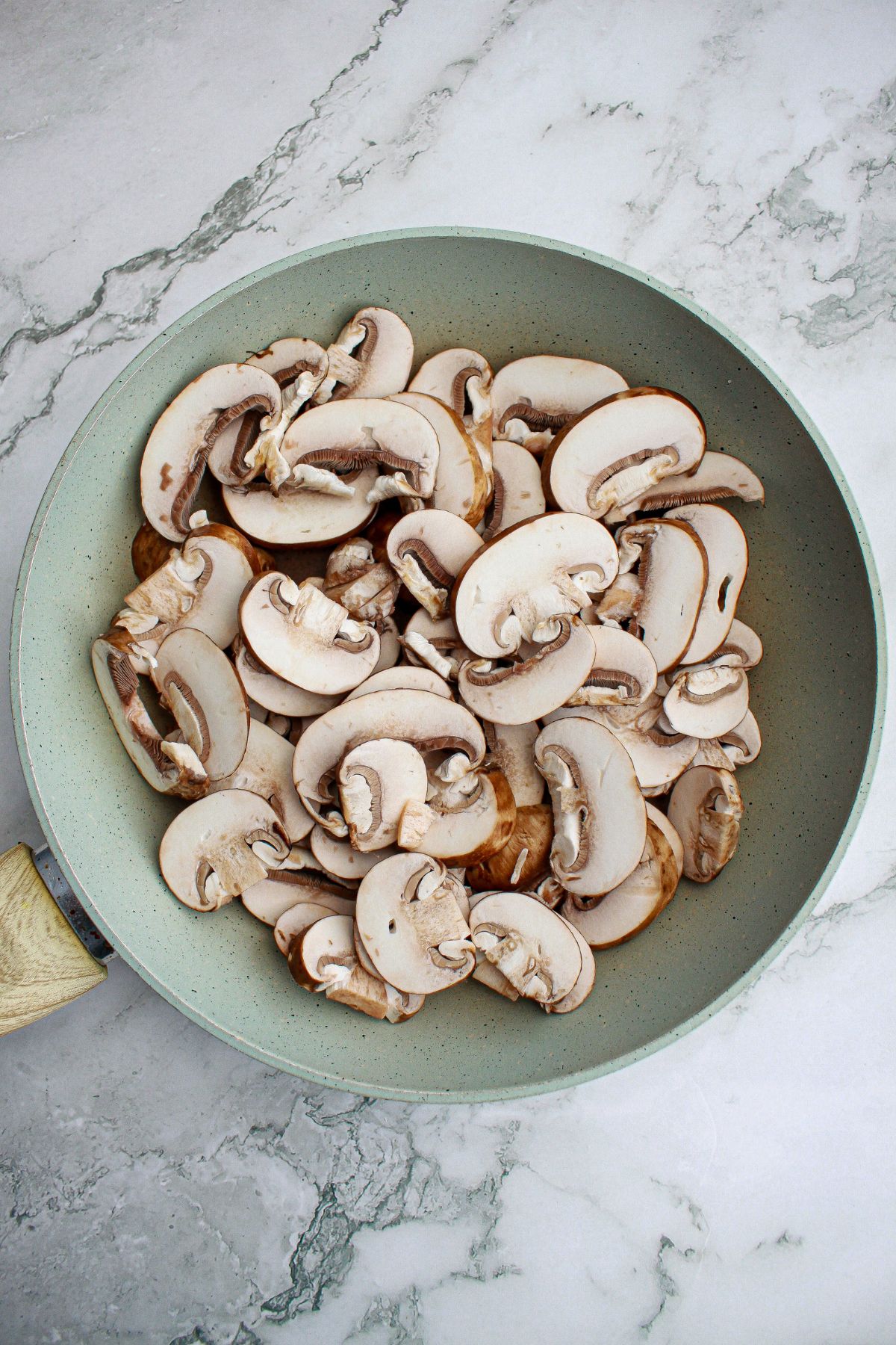 sliced mushrooms being cooked in a skillet.