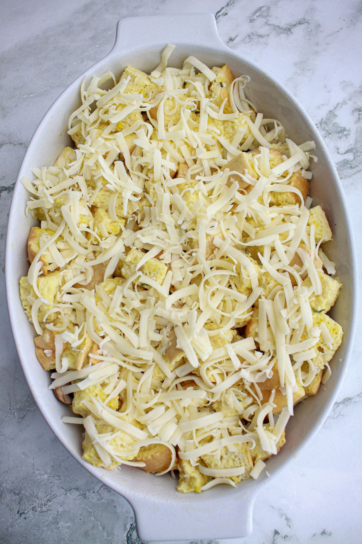 cheese being sprinkled on top of a casserole.