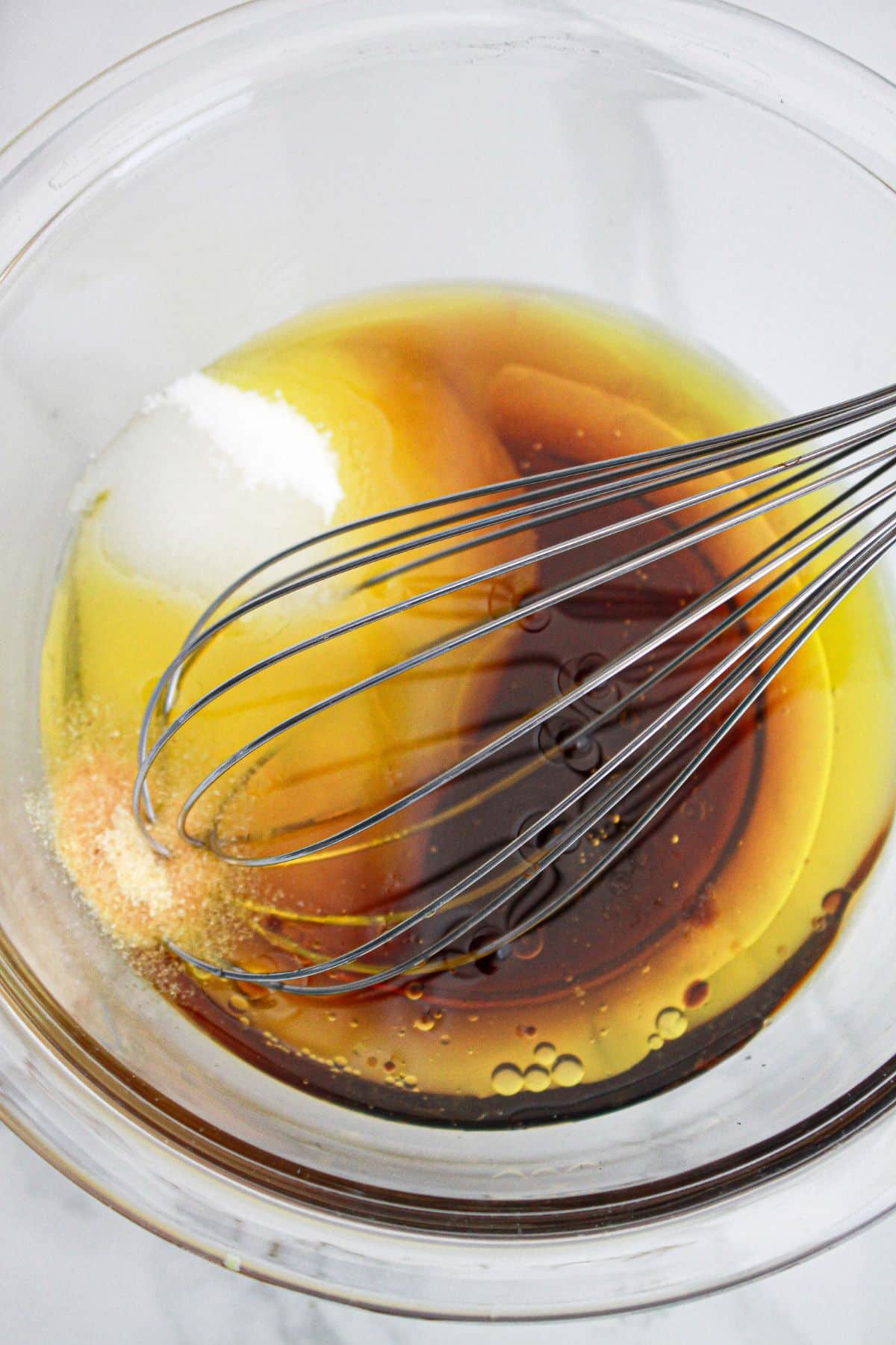sesame dressing being mixed in a large glass bowl.