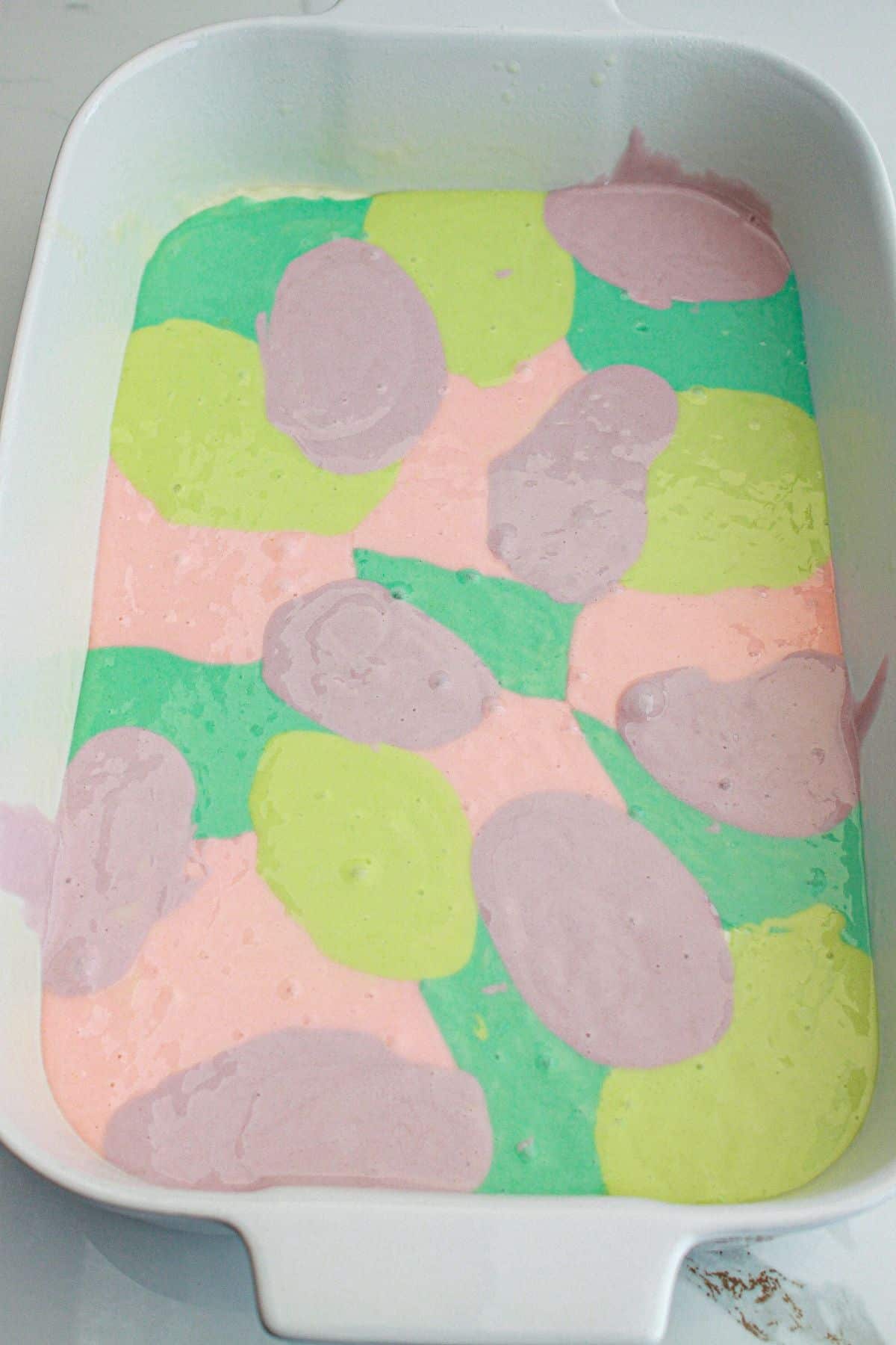 green, yellow, pink and purple batter in a casserole dish ready for the oven.
