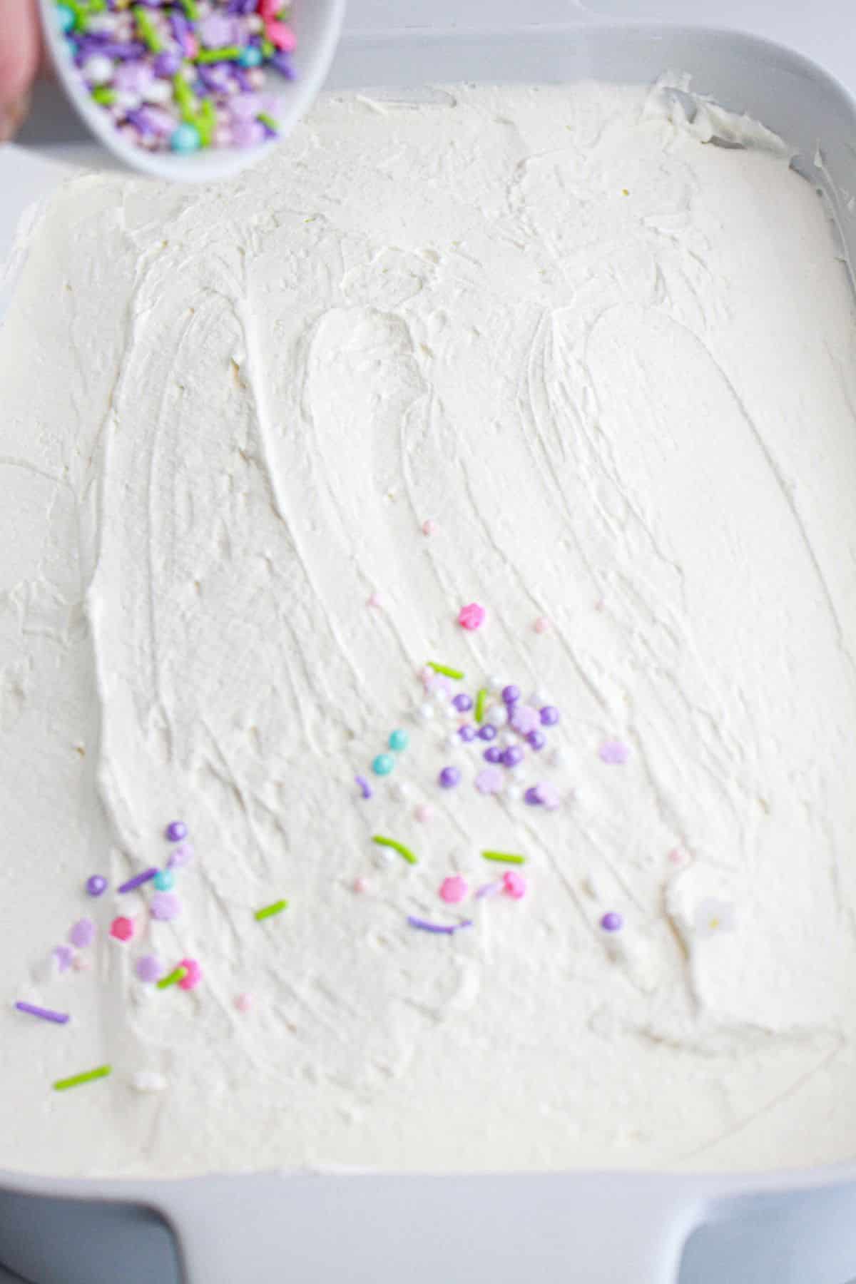 sprinkles being added on top of a cake.