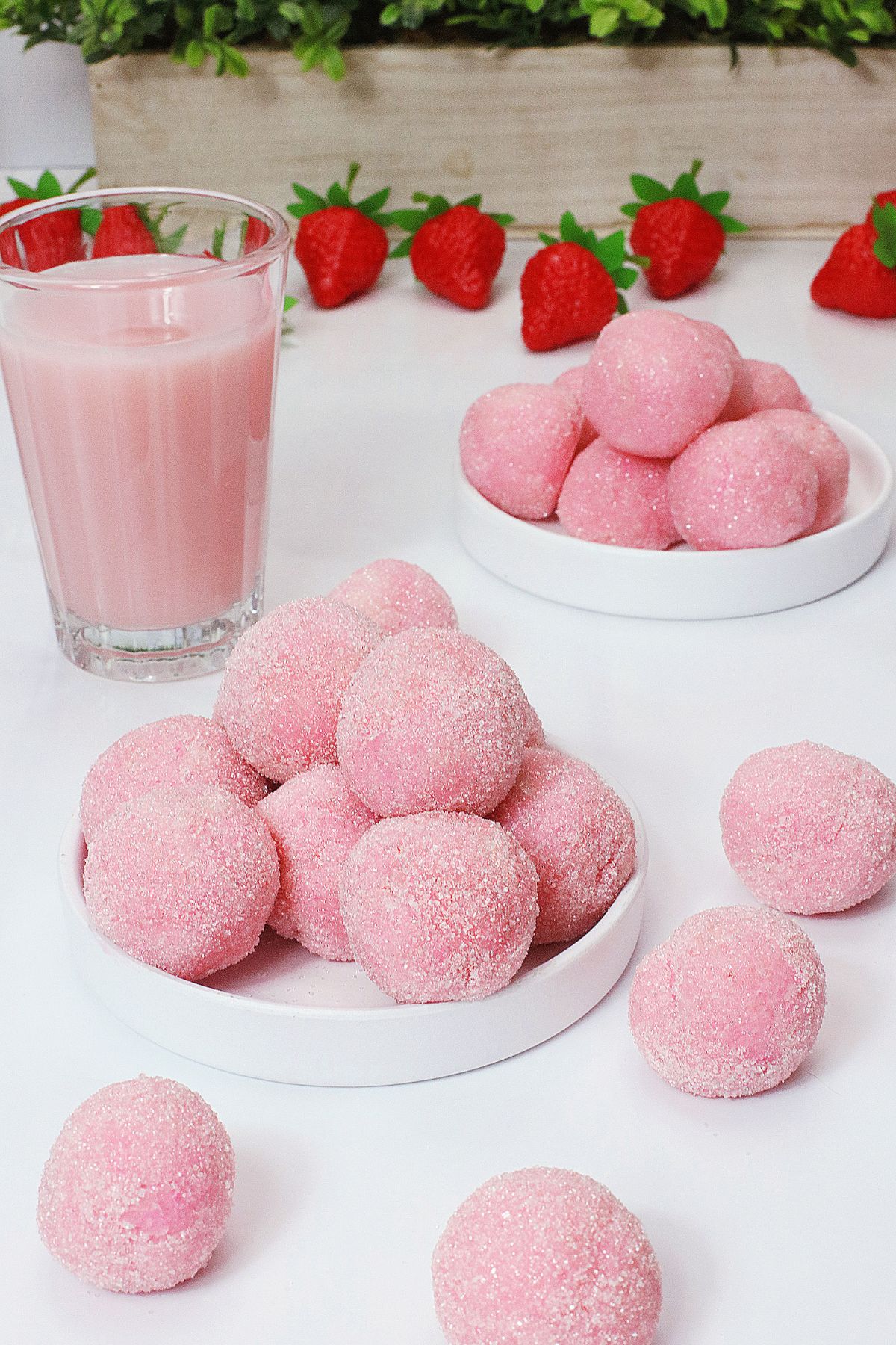 eight pink truffles stacked on a small white plate.