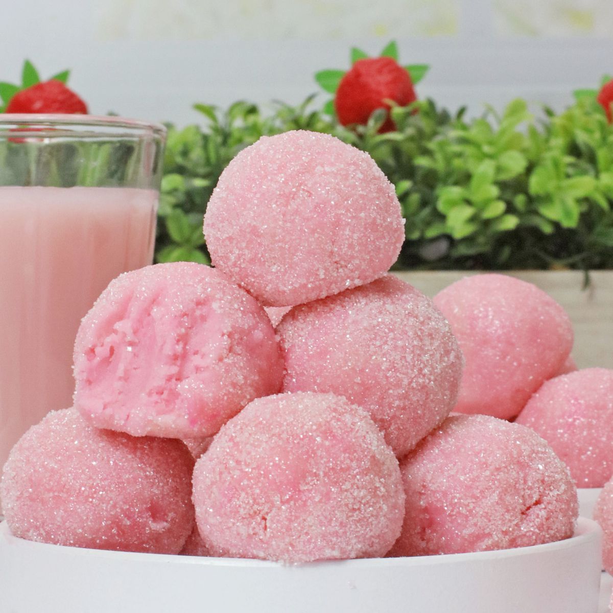 eight pink truffles stacked on a small white plate.