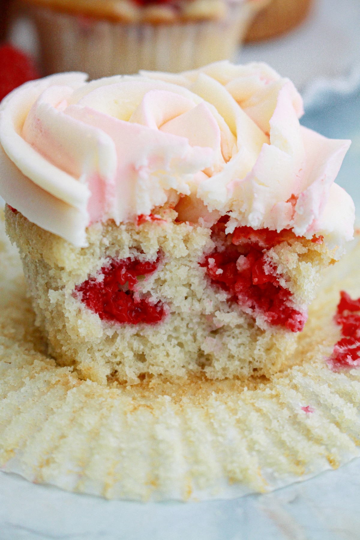 unwrapped raspberry white chocolate cupcakes with a bite missing.