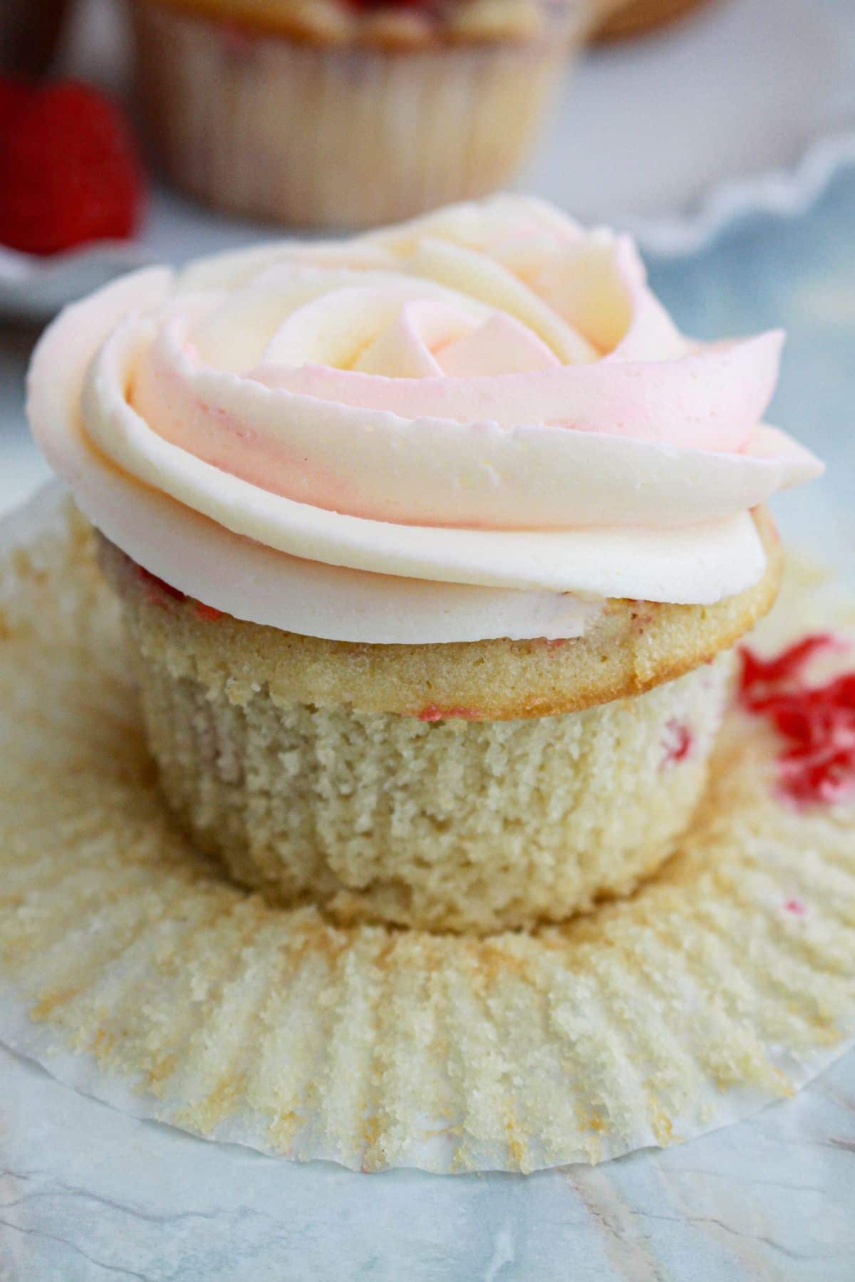 unwrapped raspberry white chocolate cupcake on a counter.