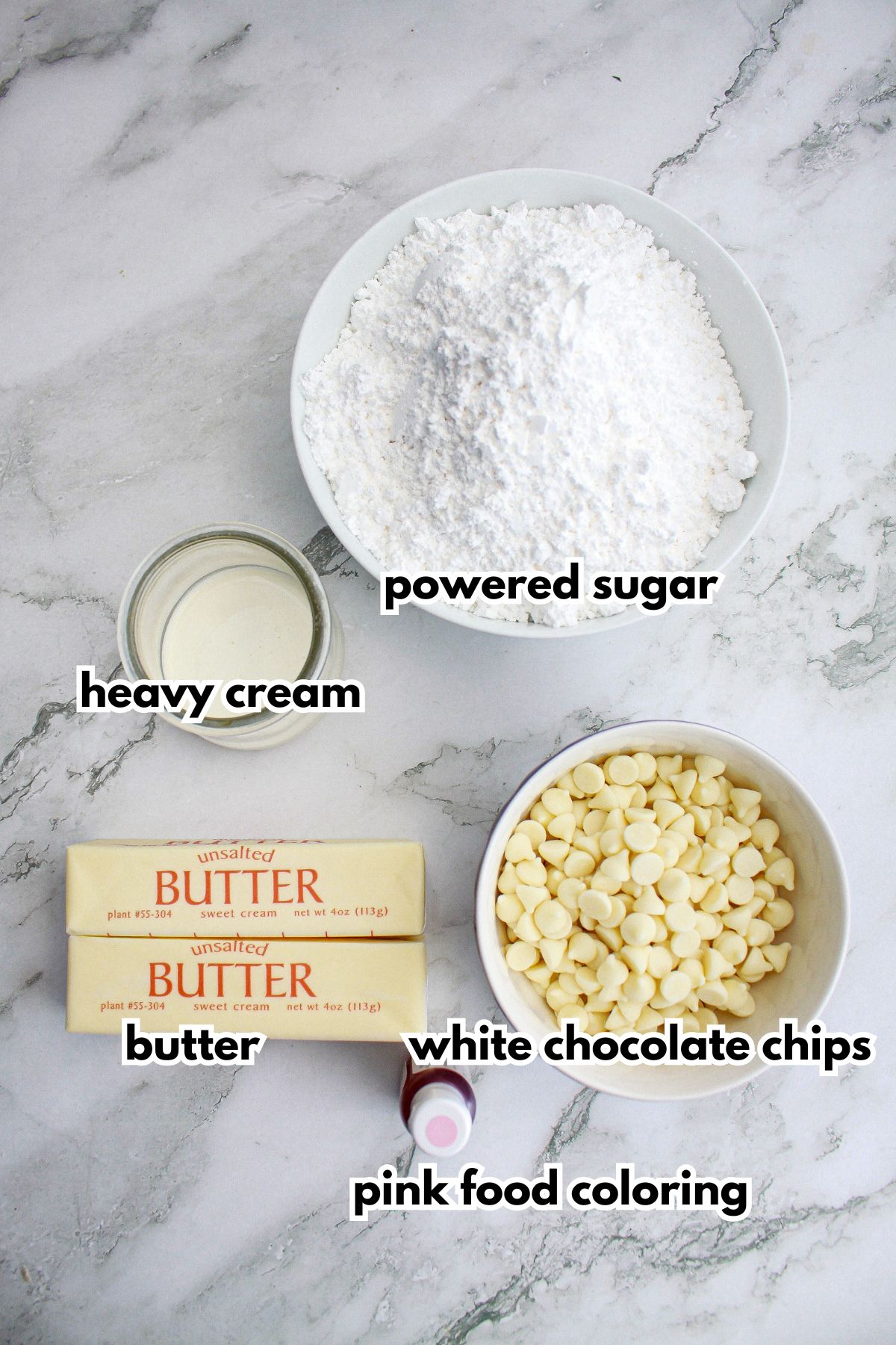 powdered sugar, heavy cream, butter, white chocolate chips, and pink food coloring on a counter.