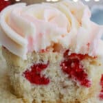 unwrapped raspberry white chocolate cupcakes with a bite missing.