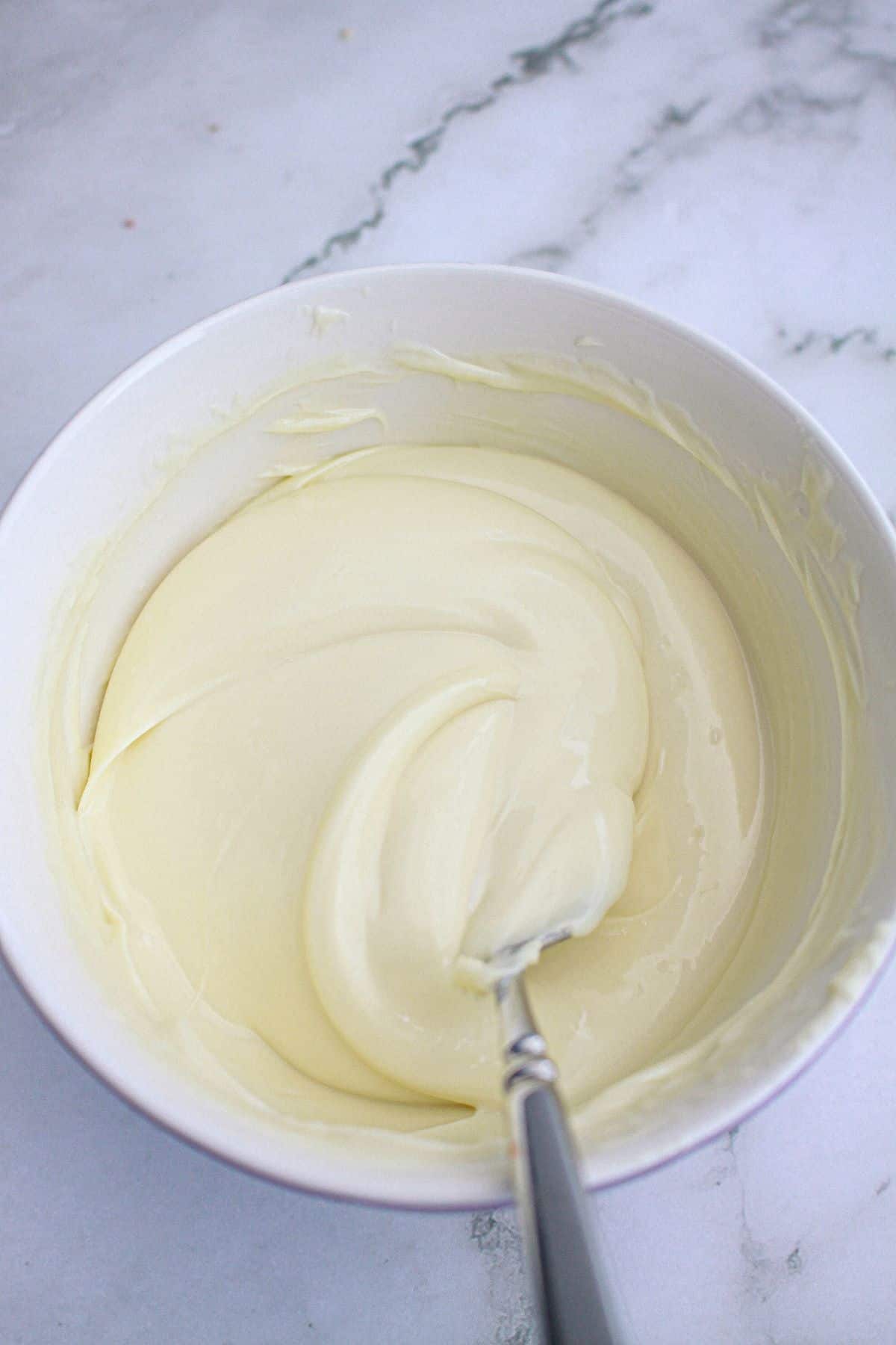 frosting being mixed in a bowl.