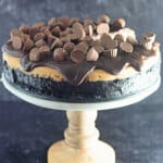 uncut reeses cheesecake on a cake stand.