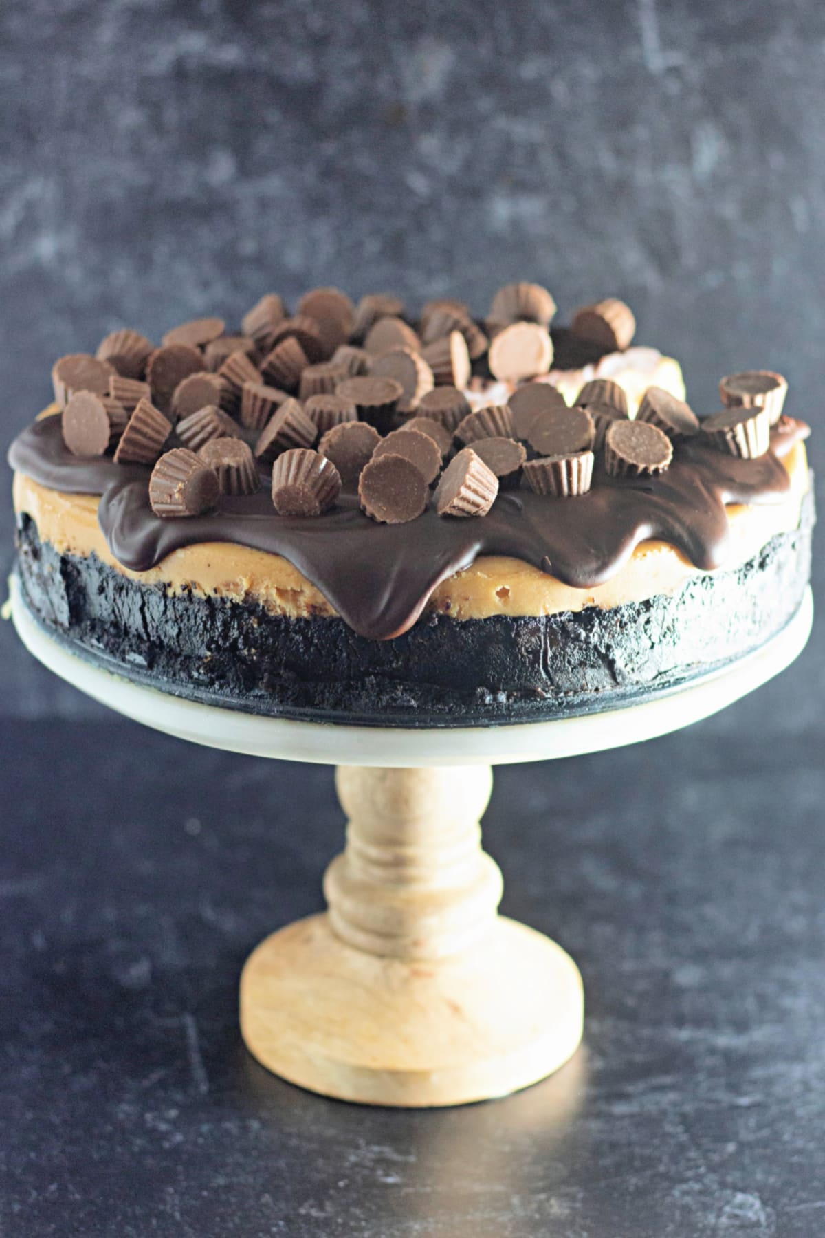 uncut reeses cheesecake on a cake stand.