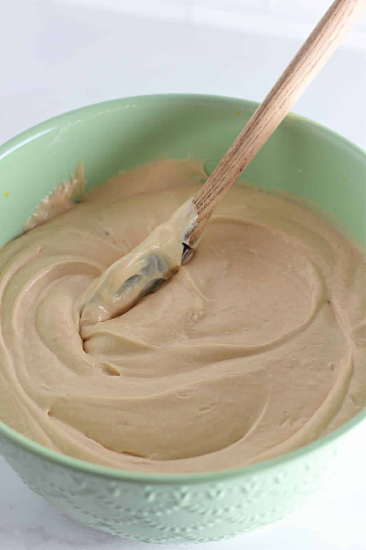 peanut butter cheesecake batter being mixed in a large bowl.