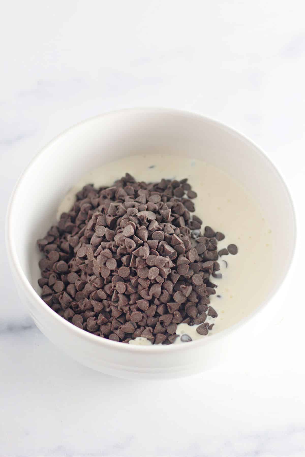 chocolate chips and heavy cream being melted in a bowl.