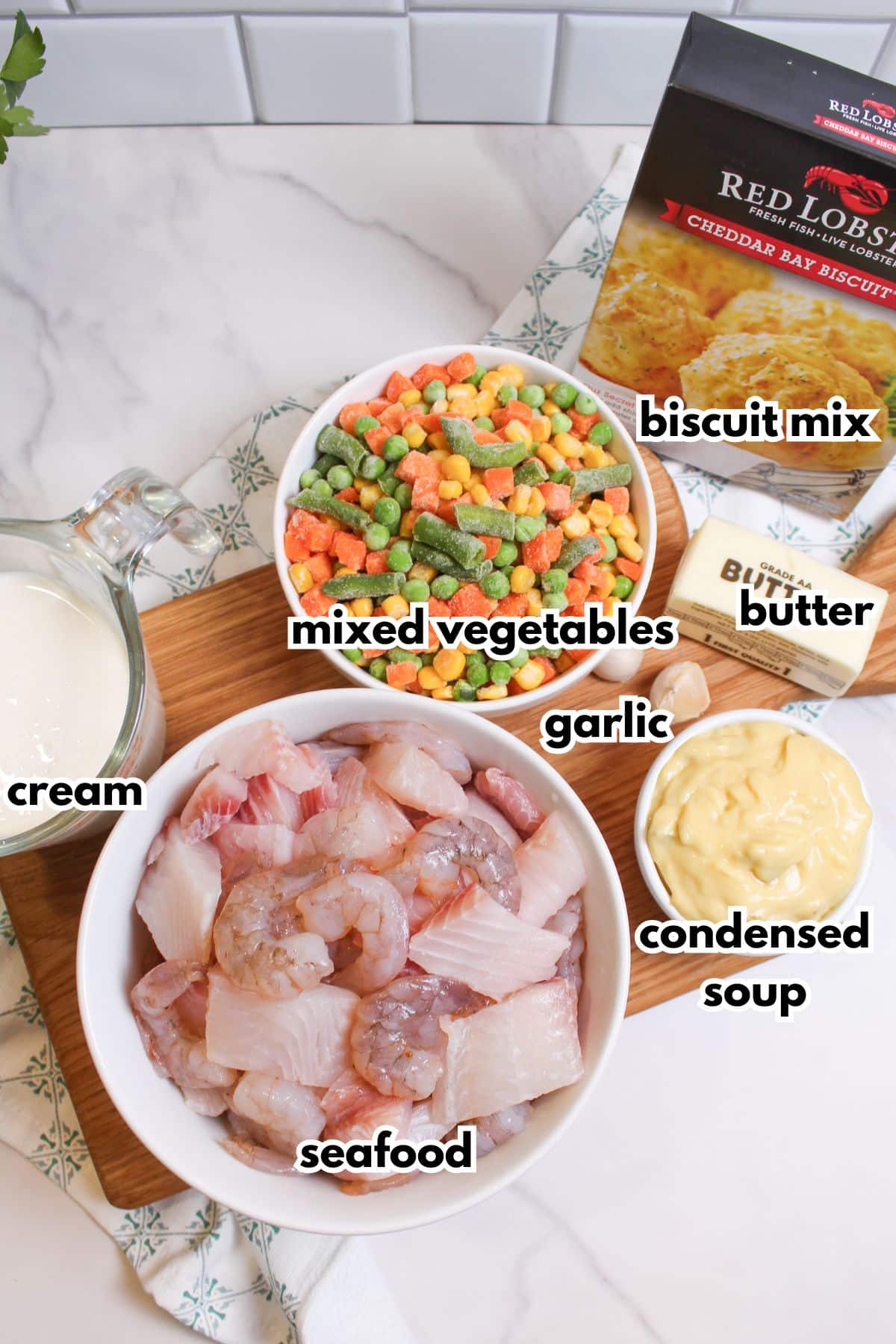 bowls of cream, seafood, mixed vegetables, garlic, butter, condensed soup, and a box of biscuit mix.