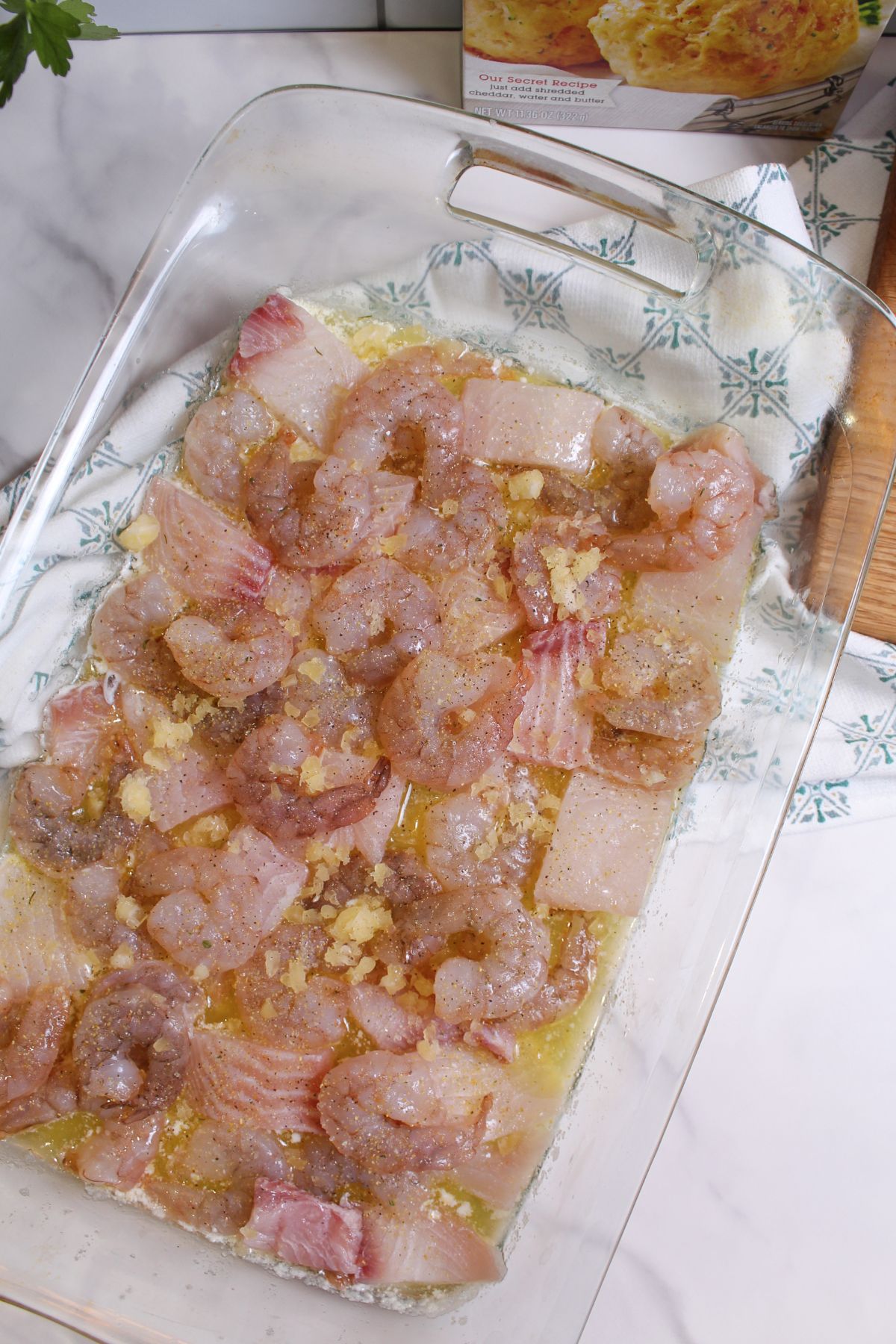 shrimp and fish added to a glass casserole dish.