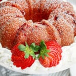 uncut strawberry bundt cake surrounded by whipped cream.