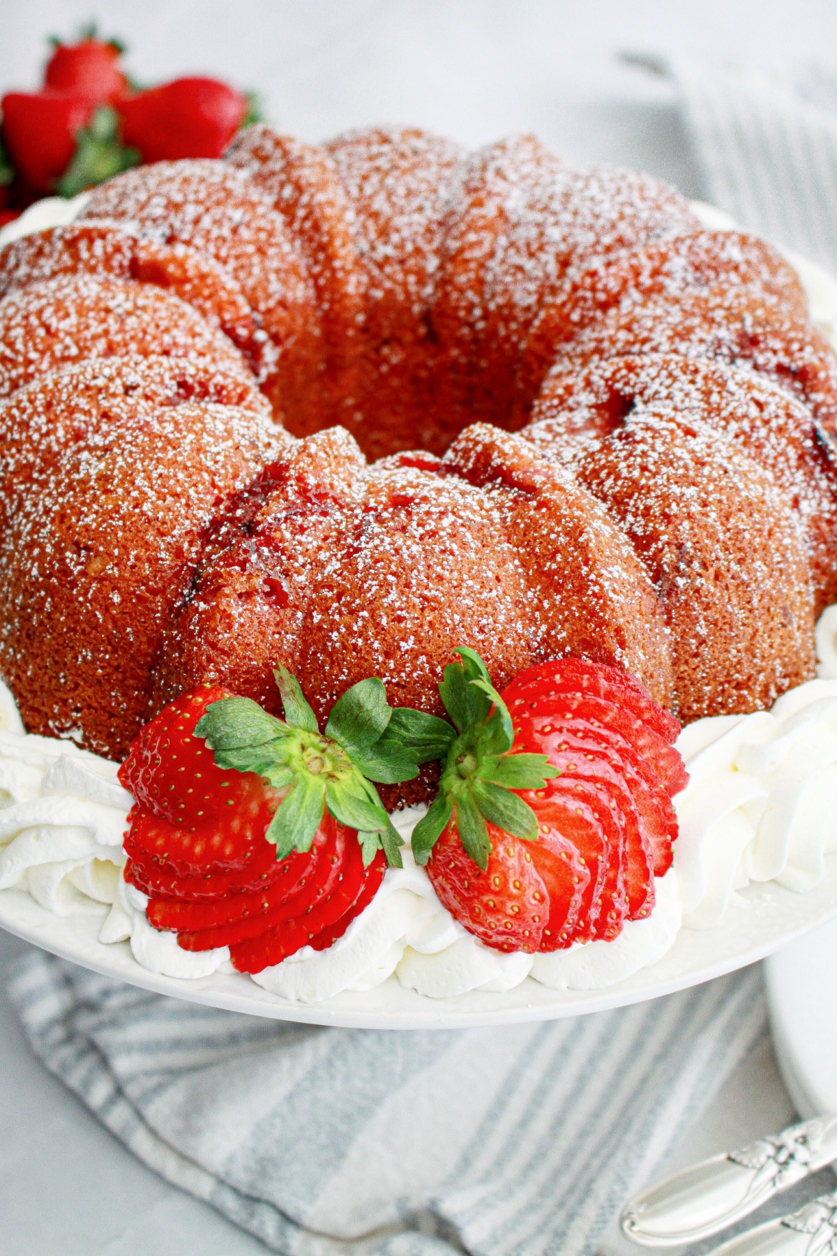 uncut strawberry bundt cake surrounded by whipped cream.
