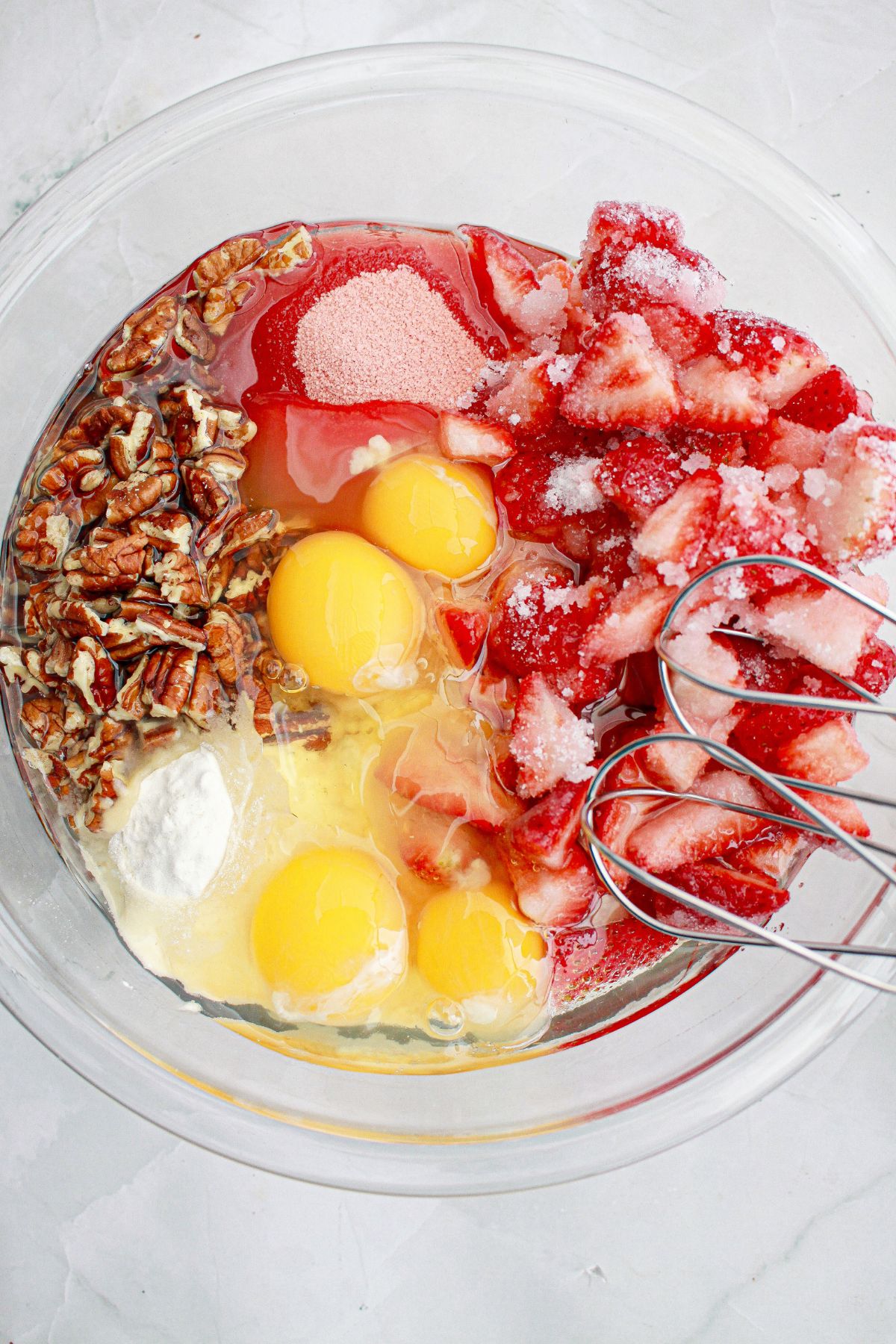 cake batter being combined together in a large glass bowl.